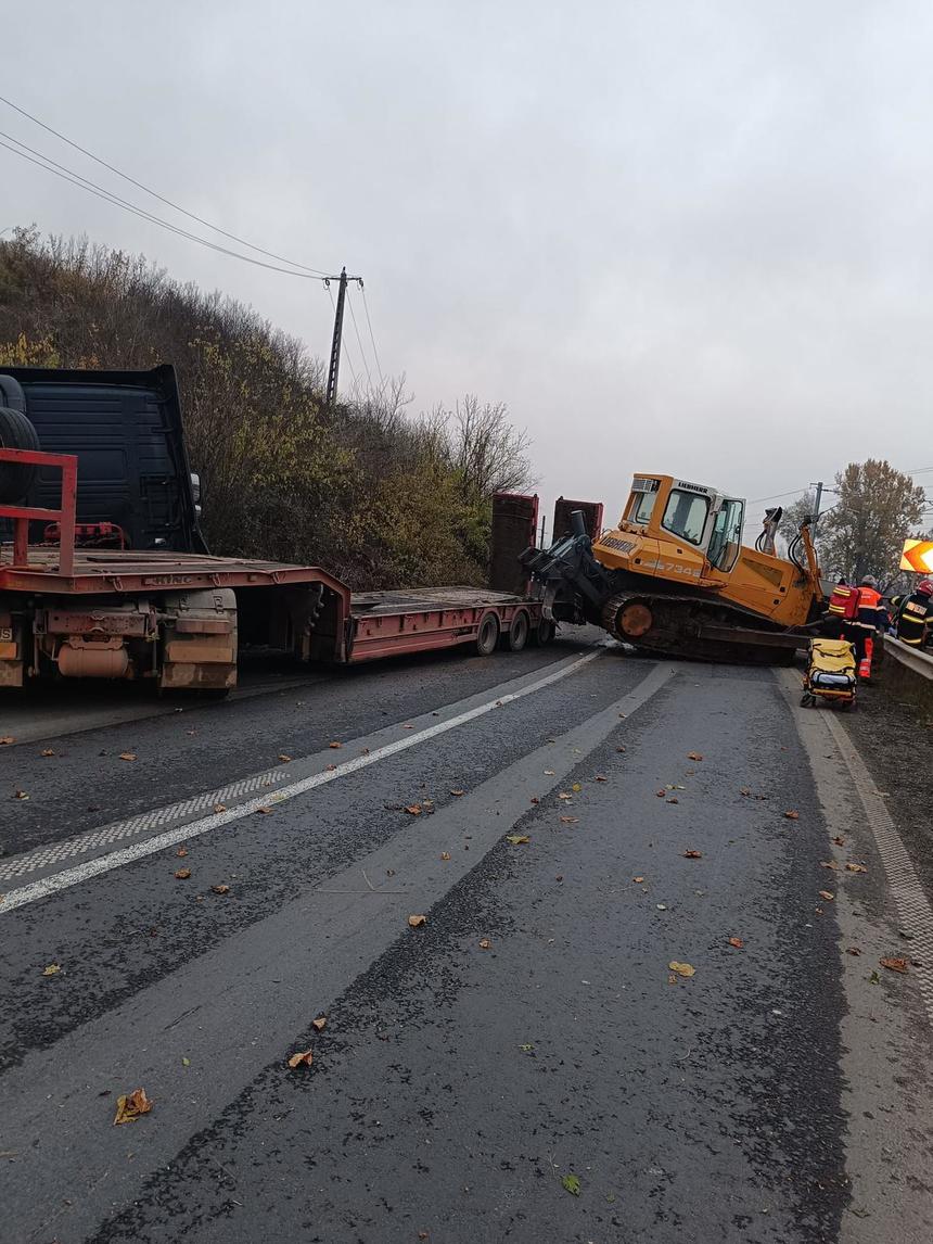 Într o curbă un excavator transportat a căzut peste o mașină o tânără