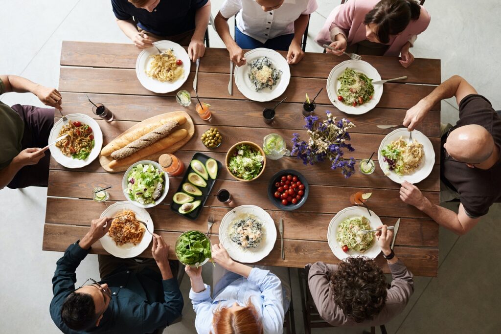 oameni mâncând la o masă de lemn