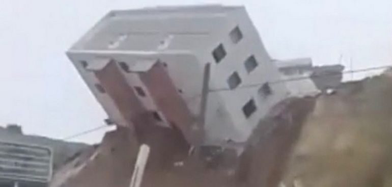 Imagini spectaculoase: O clădire cu trei etaje alunecă pe un deal, se răstoarnă și apoi cade peste șosea (Video)