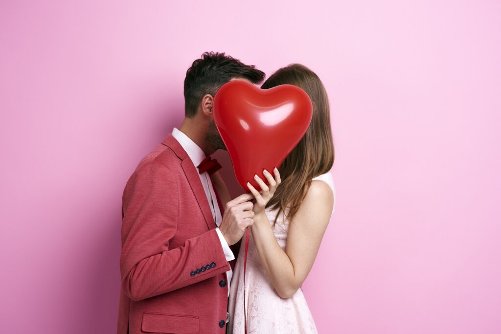 Affectionate couple covering face with balloon and