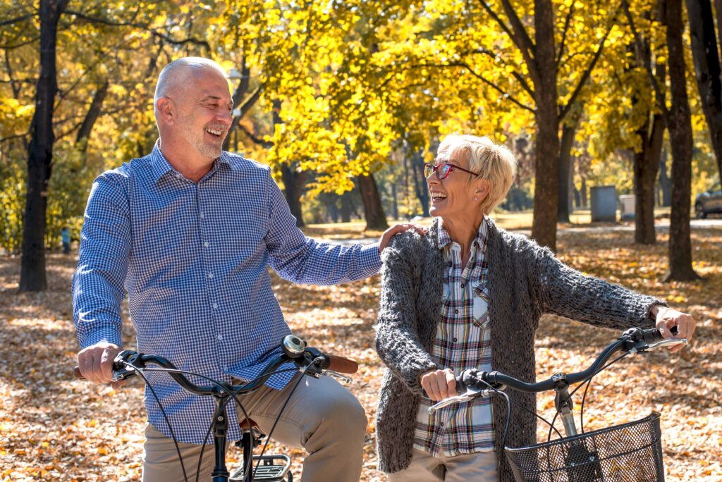 Happy elderly couple riding a bicycle in the park 