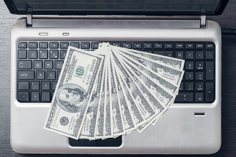 Dollars on laptop keyboard. Top view. Business and