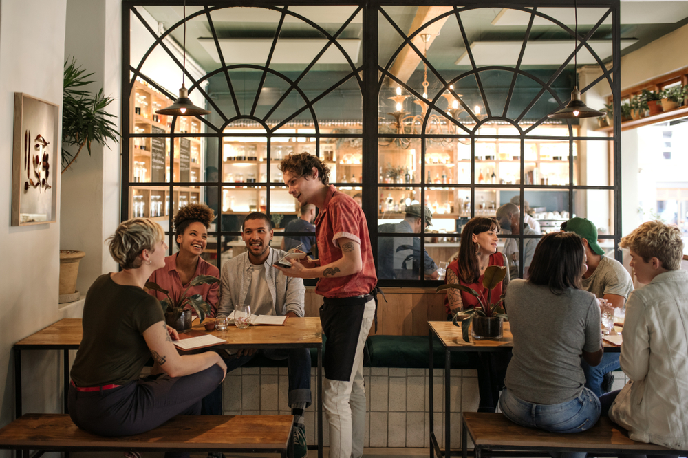 Smiling,Young,Waiter,Taking,Orders,From,A,Diverse,